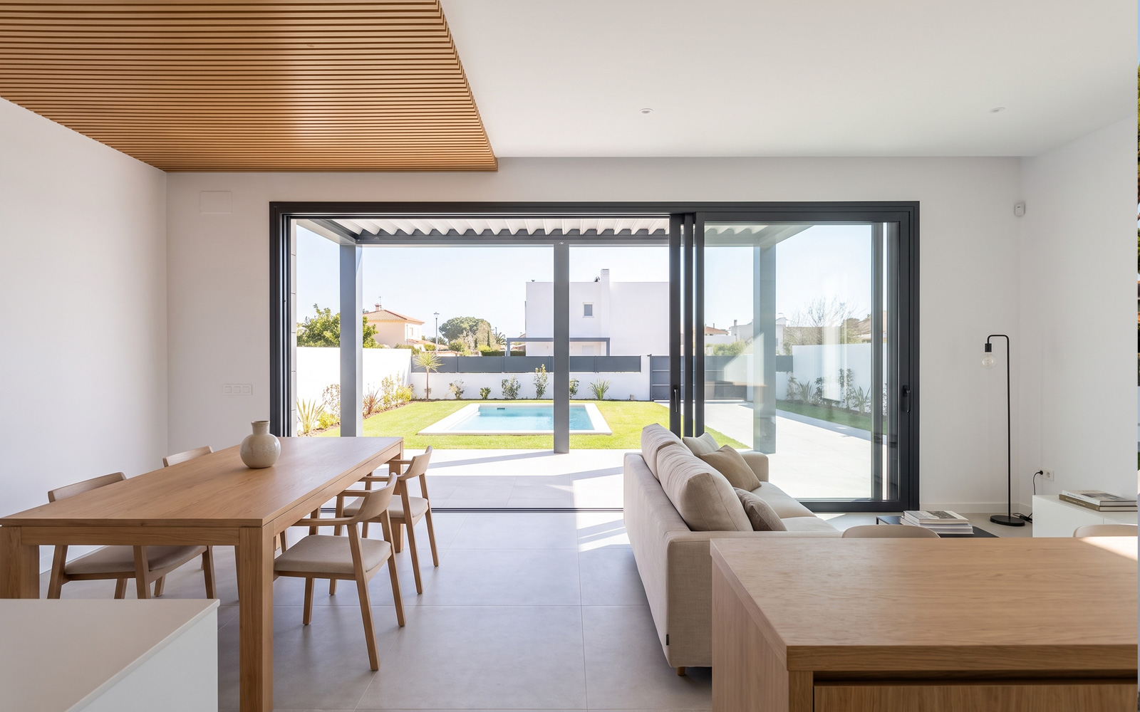 Salón con grandes correderas al jardín y techo de lamas de madera