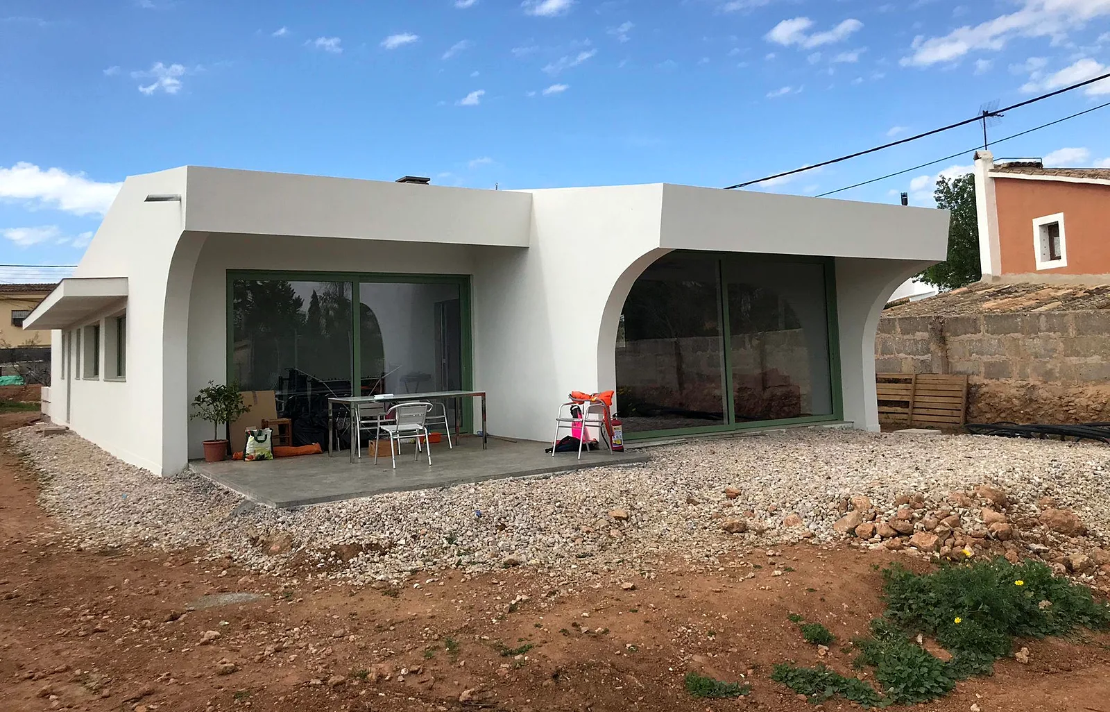 Casa de madera de entramado ligero con fachada monocapa blanca y arcos
