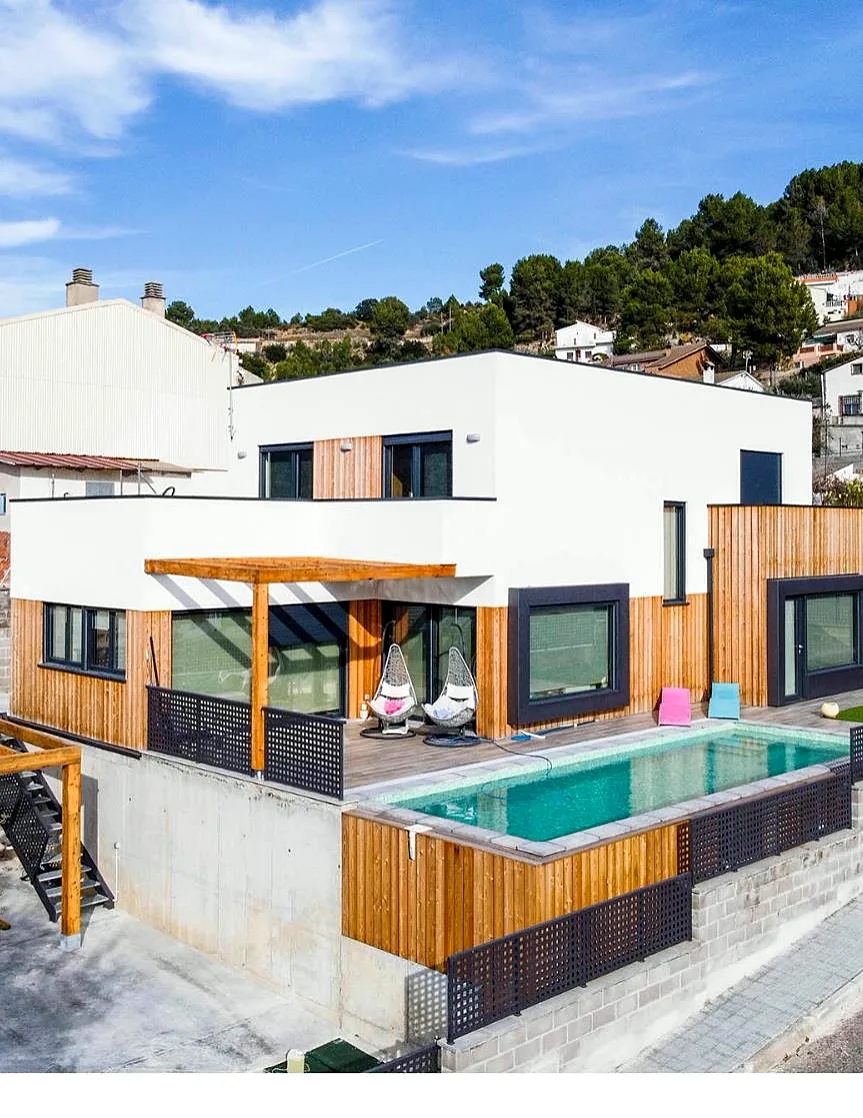 Casa de madera de entramado ligero con fachada blanca y madera, porche y piscina