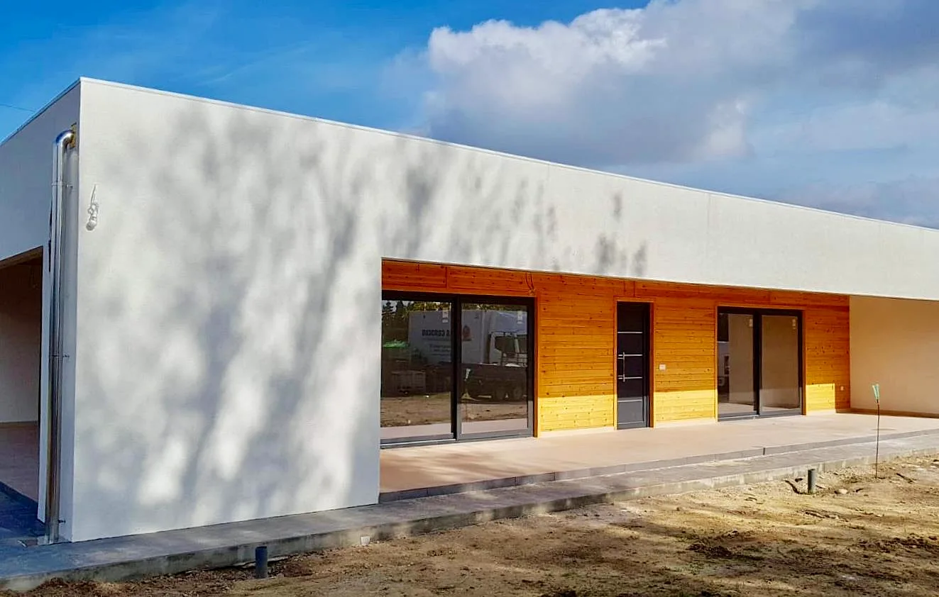 Casa de madera de una planta con fachada blanca y porche revestido de madera